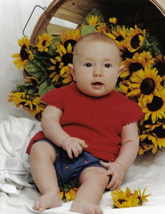 Domino, in red top with blue bottoms, basket of sunflowers in background