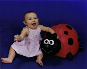 Domino, smiling in a white dress with a pink background